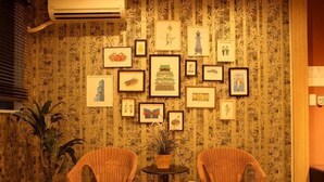A room with patterned wallpaper, two wicker chairs, a small table, and framed pictures on the wall. - Rakuyado Turuhashi (Osaka)