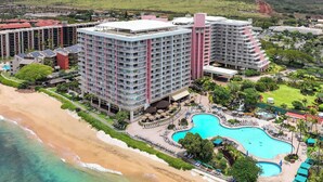 Een hoog hotel met meerdere verdiepingen, een zwembad en een ligging aan het strand.