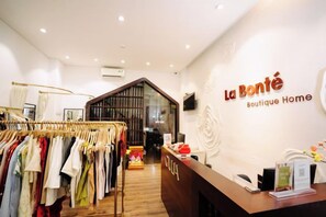 A boutique hotel interior with a clothing rack, reception desk, and a large mirror. - La Bonté Boutique Home Ho Chi Minh (Ho Chi Minh City)