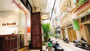Egy butikhotel bejárata, melynek homlokzata fából készült, van rajta egy üvegajtó, és egy „La Bonté Boutique Home” feliratú tábla.