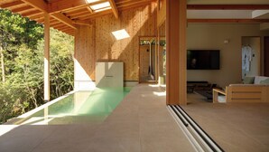 A modern interior with a wooden ceiling, a glass pool, and a TV in the living area. - Casablanca Villa Hakone (Hakone)
