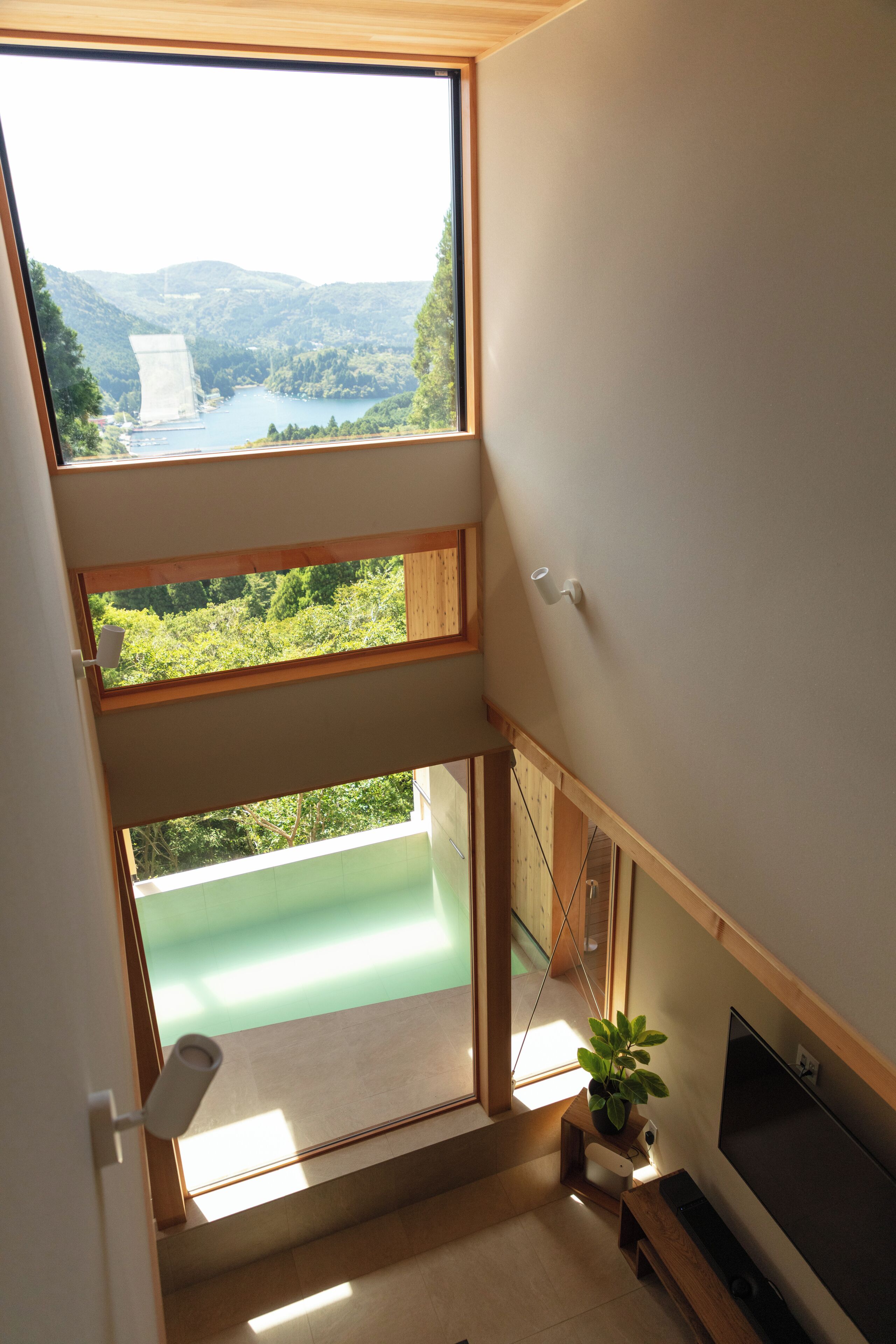 A modern interior with a large skylight, a flat-screen TV, and a view of a lake and mountains.