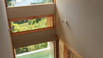 A modern interior with a large skylight, a flat-screen TV, and a view of a lake and mountains.