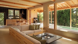 A modern living room with a sofa, a coffee table, and large windows offering a view of the outdoors. - Casablanca Villa Hakone (Hakone)