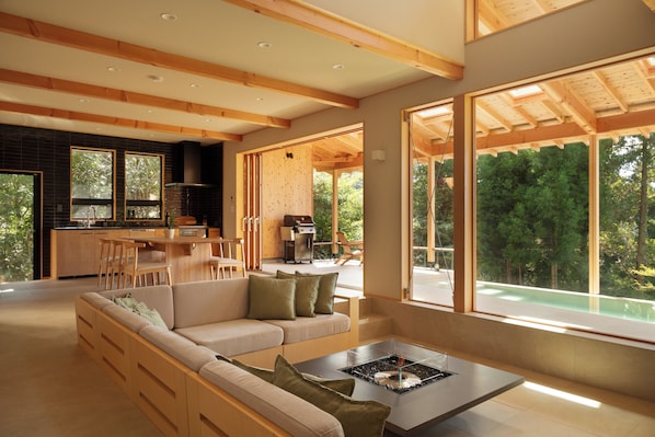 Una sala de estar moderna con un sofá, una mesa de centro y ventanas amplias que dan a vistas del exterior.