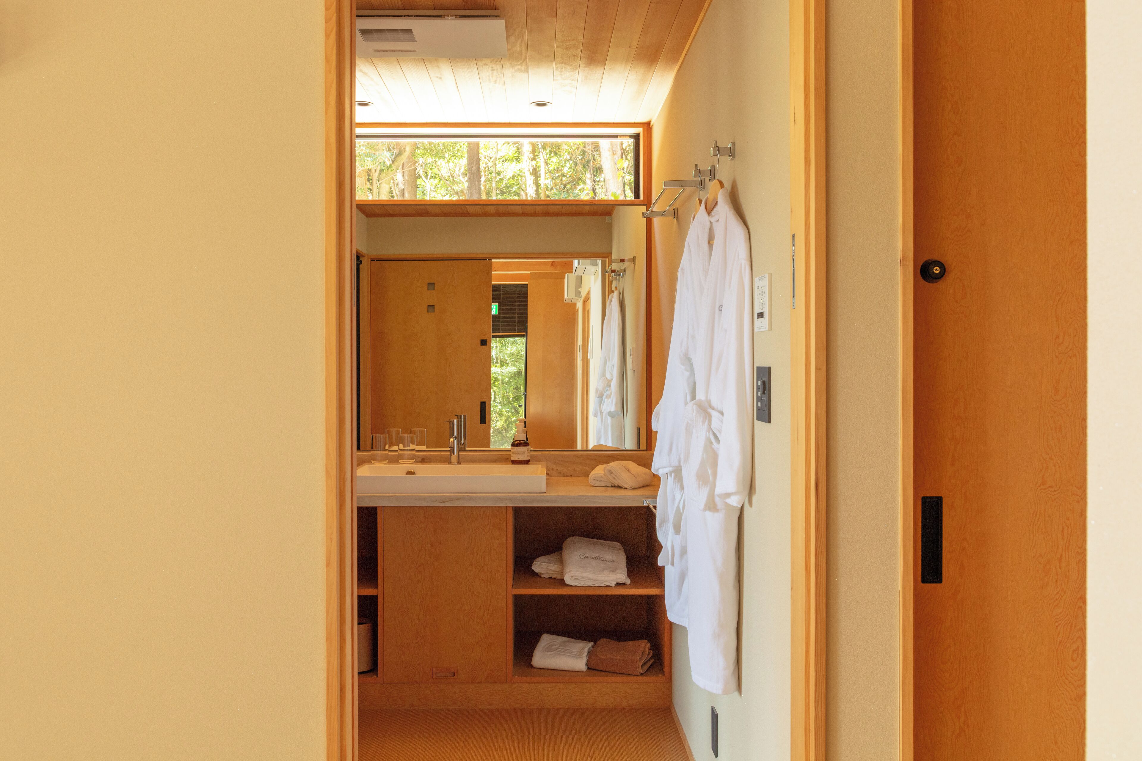 A bathroom with a wooden vanity, a large mirror, and a towel rack.