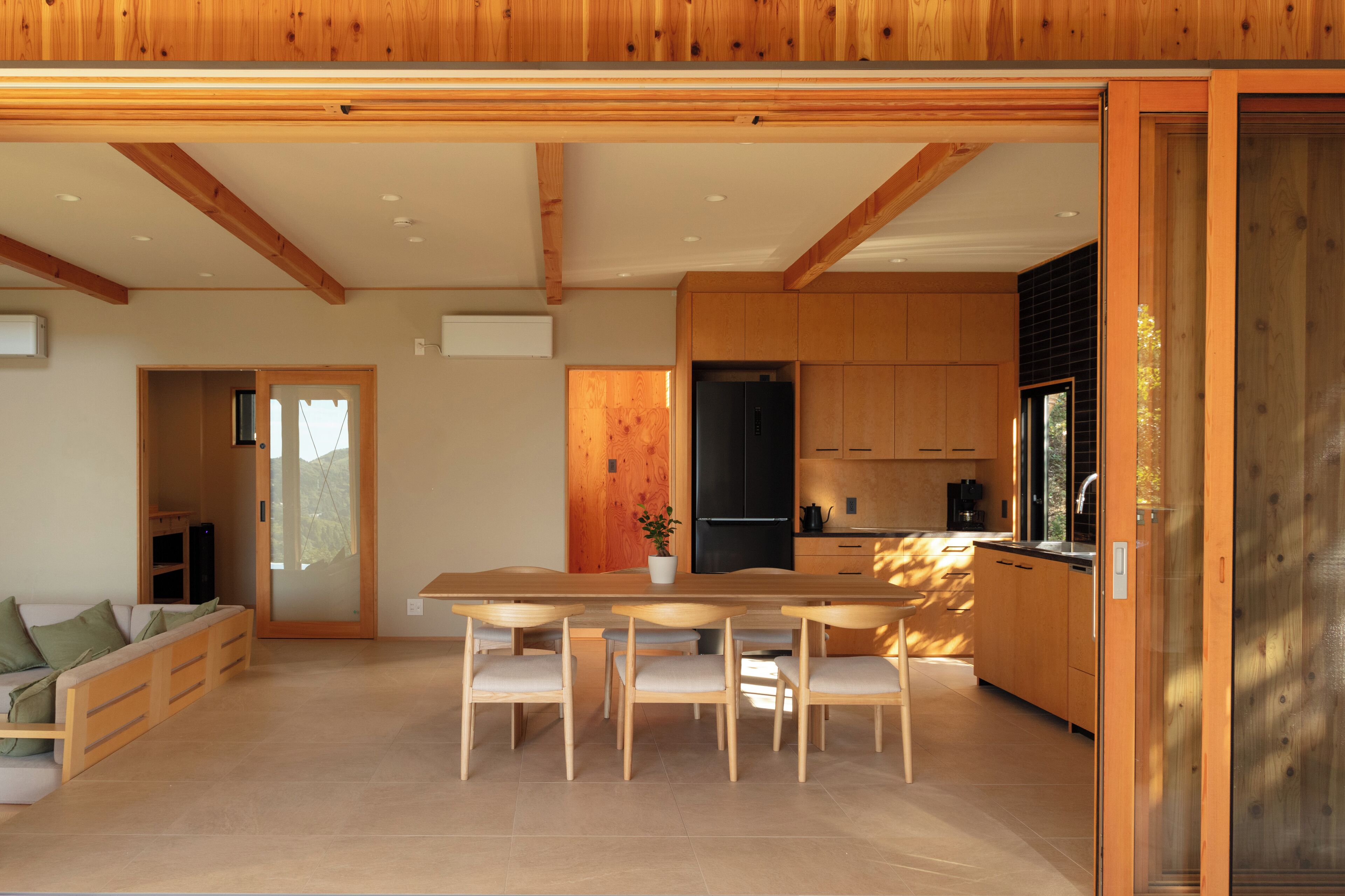 A modern kitchen with wooden cabinets, a central island, and a dining area with chairs.