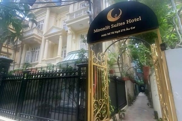 Entrada de un hotel con un cartel que dice 'Moonlit Suites Hotel'.