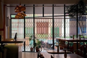 A modern interior with a dining area, large windows with metal grilles, and hanging pendant lights. - Some Place Else (George Town)
