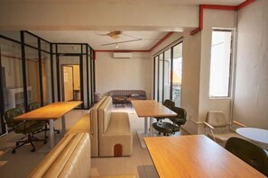 Ein modernes Interieur mit einem langen Holztisch, gepolsterten Sitzgelegenheiten und Blick durch große Fenster.