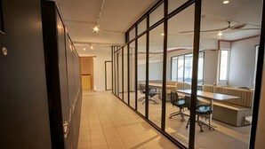 Un espacio de oficina moderno con separaciones de vidrio, un largo pasillo y varios puestos de trabajo.