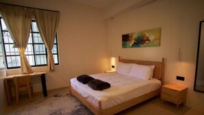Un dormitorio con una cama de madera, un escritorio y una silla. Hay un cuadro en la pared y una ventana con cortinas.