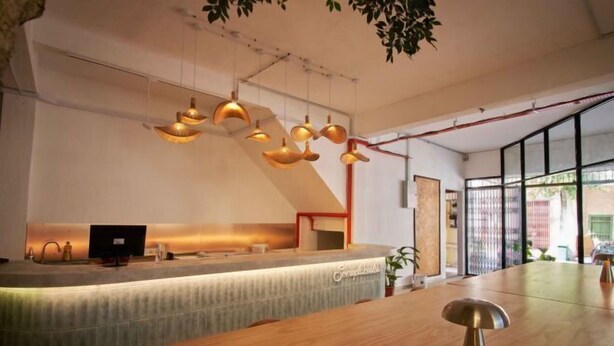 Una moderna zona de recepción con un mostrador de madera, una computadora y un área de asientos.