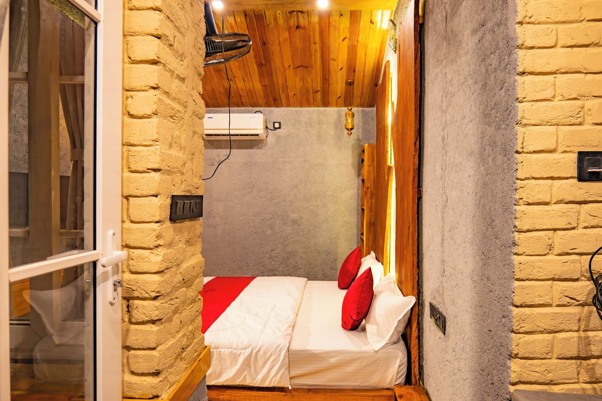 Una habitación pequeña y acogedora con una cama, una ventana y techo de madera.