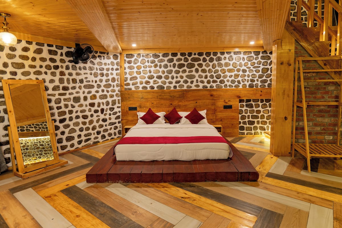 Una cama con estructura de madera, un fondo de pared de piedra, una escalera de madera y un suelo con diseño.