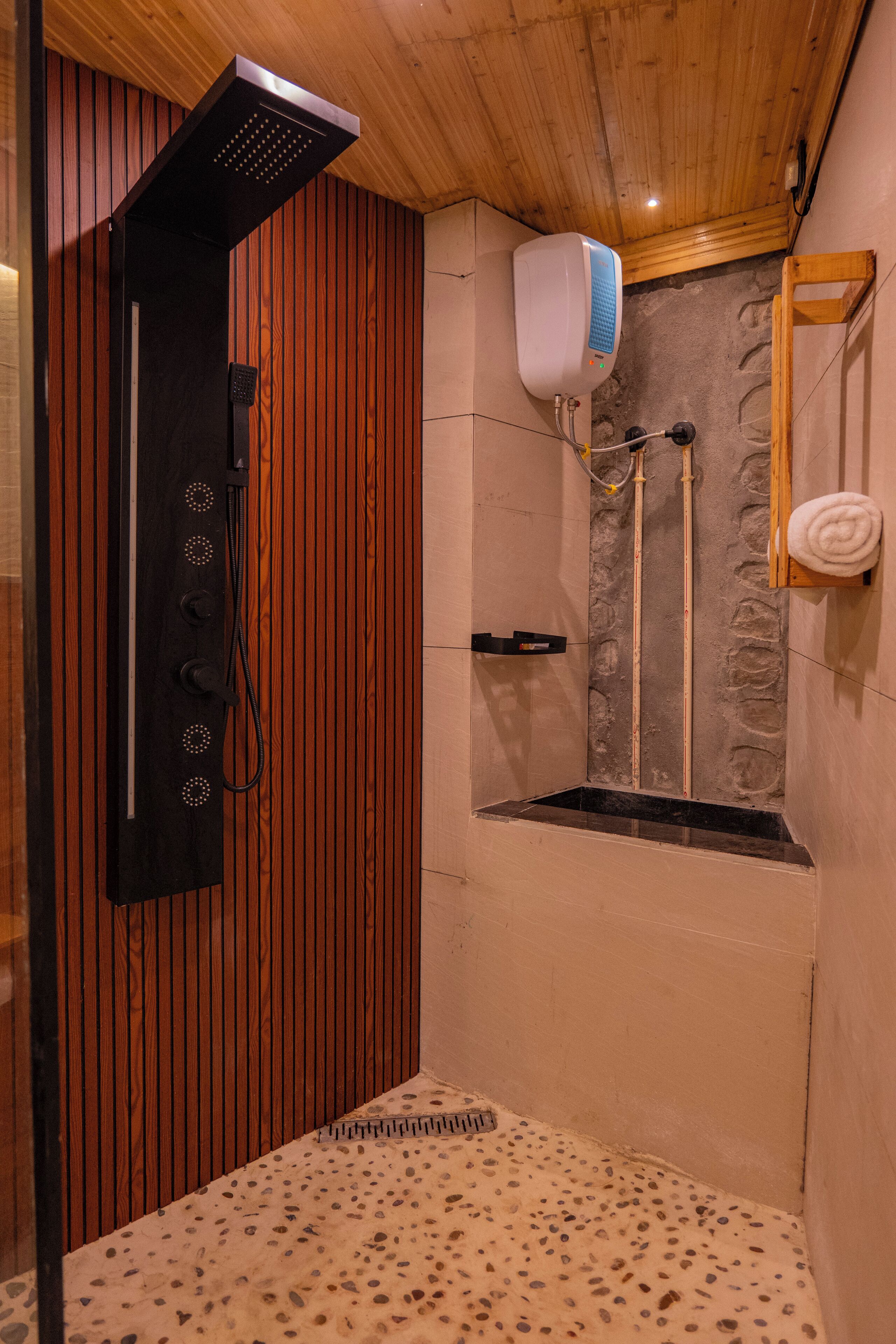 A shower area with a wooden panel wall, a stone wall, and a towel rack.