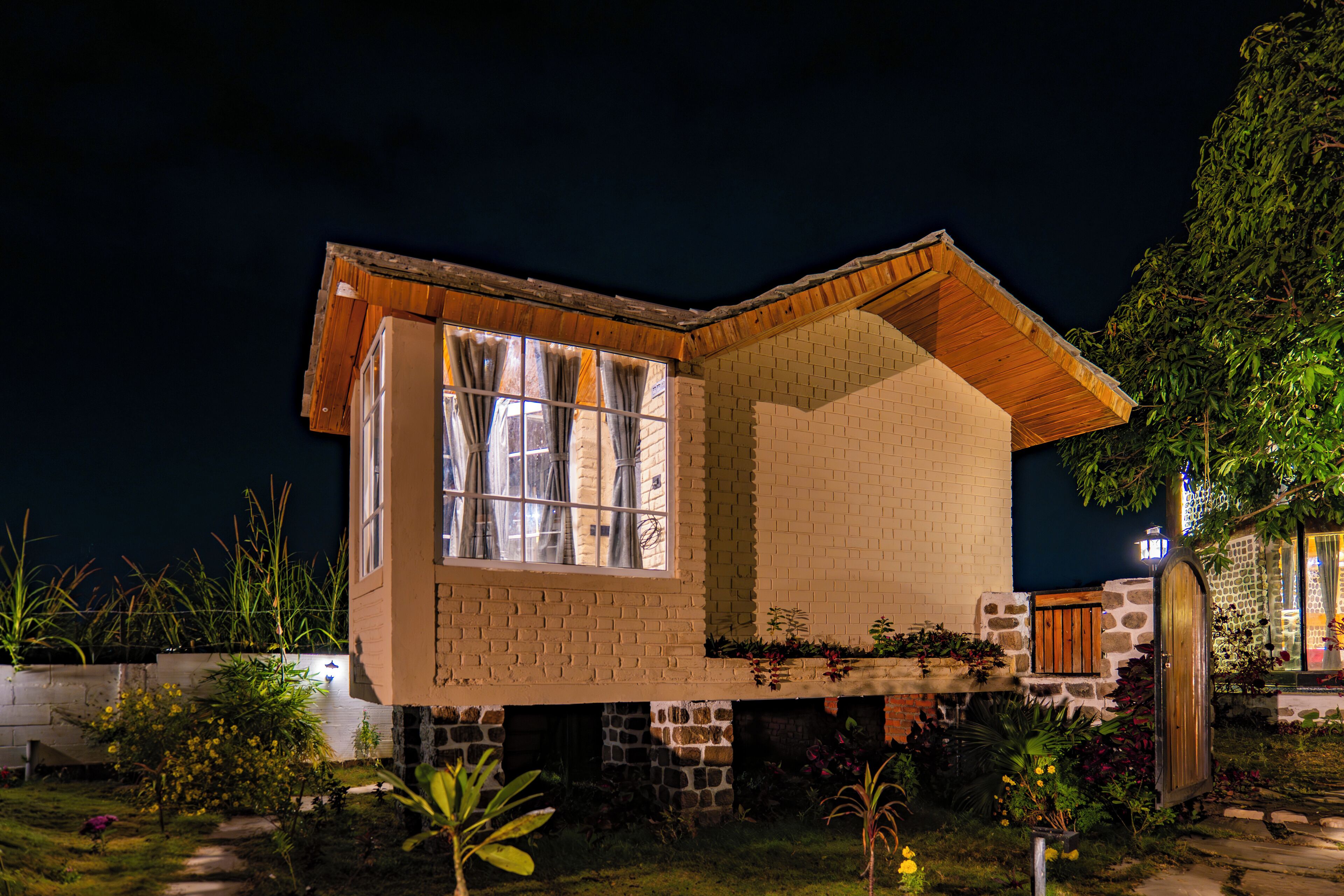 Une maison à deux étages avec une façade en briques, une grande fenêtre au rez-de-chaussée et une porte en bois.