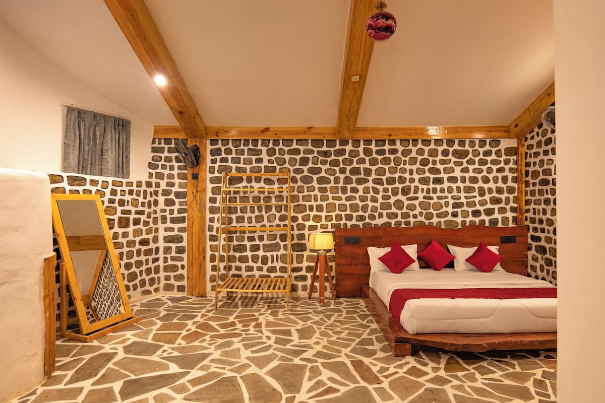 Un dormitorio con piso de diseño de piedra, estructura de cama de madera y pared de piedra.
