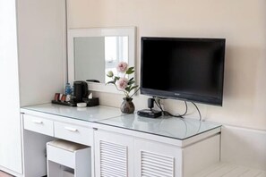 A modern hotel room with a glass-top desk, a flat-screen TV mounted on the wall, a vase with flowers, and a coffee maker. - Horizon Hotel Apartment (Hanoi)