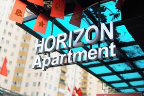 A sign for 'HORIZON Apartment' with a clear view of the building's facade and red flags. - Horizon Hotel Apartment (Hanoi)