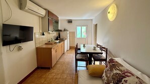 Un espacio habitable compacto con kitchenette, comedor y sofá.