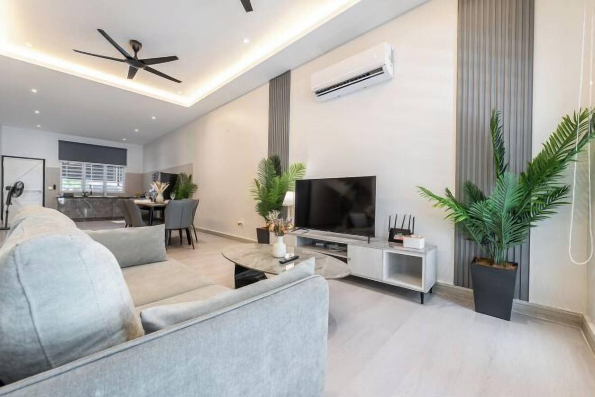 A modern living room with a sofa, TV, and plants.