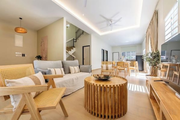 A modern living room with a sofa, chairs, a coffee table, and a TV. - La Ferringhi Villa by BRB (Batu Ferringhi)