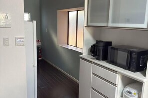 A compact kitchen with a microwave, coffee maker, and a small window. - Yodogawa Flower Private Accommodation (Osaka)