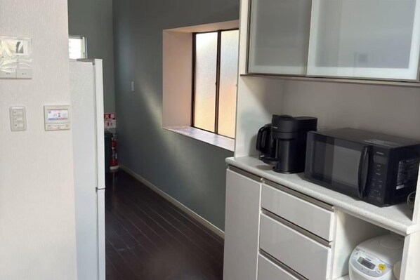 A compact kitchen with a microwave, coffee maker, and a small window. - Yodogawa Flower Private Accommodation (Osaka)