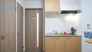 A compact kitchen with wooden cabinets, a built-in stove, and a sink. - Yodogawa Flower Private Accommodation (Osaka)