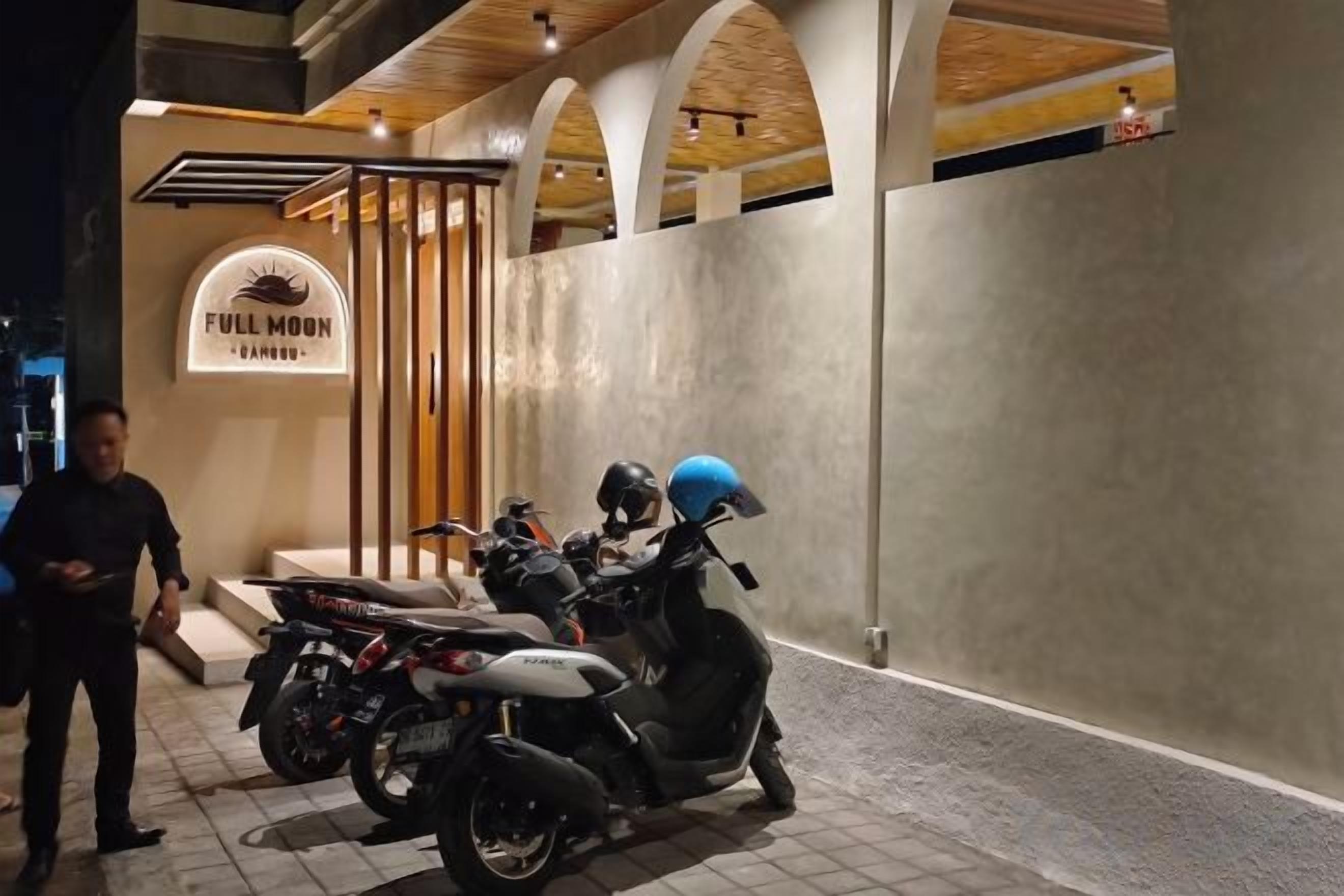 Zona de exhibición de motocicletas con un cartel que dice 'FULL MOON' y una persona parada cerca.