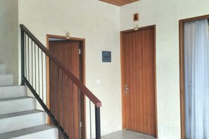 A staircase with a wooden handrail leading to a door with a sign above it. - Fullmoon Canggu Nelayan (Bali)