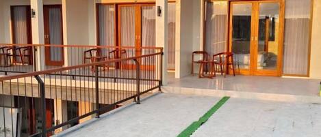 A hotel exterior with a covered outdoor seating area, a staircase, and a glass door entrance.