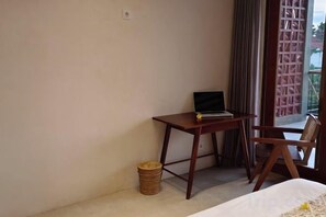 Una habitación con una cama, un escritorio pequeño con una computadora portátil, una silla, un cesto de basura y vistas al exterior.