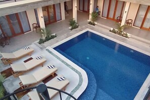Una piscina con sillas de descanso y un patio cubierto.