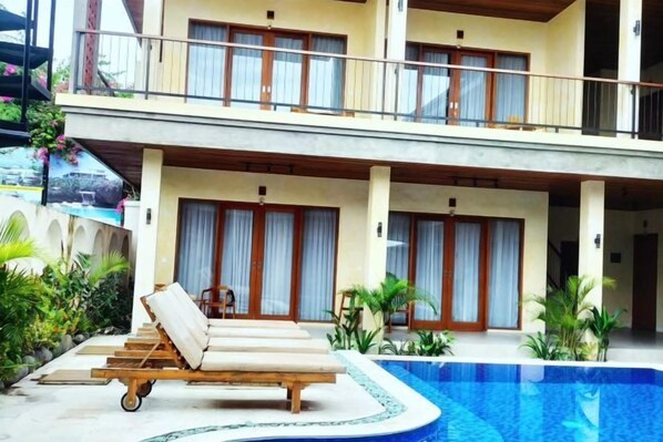 A poolside area with lounge chairs and a swimming pool. - Fullmoon Canggu Nelayan (Bali)
