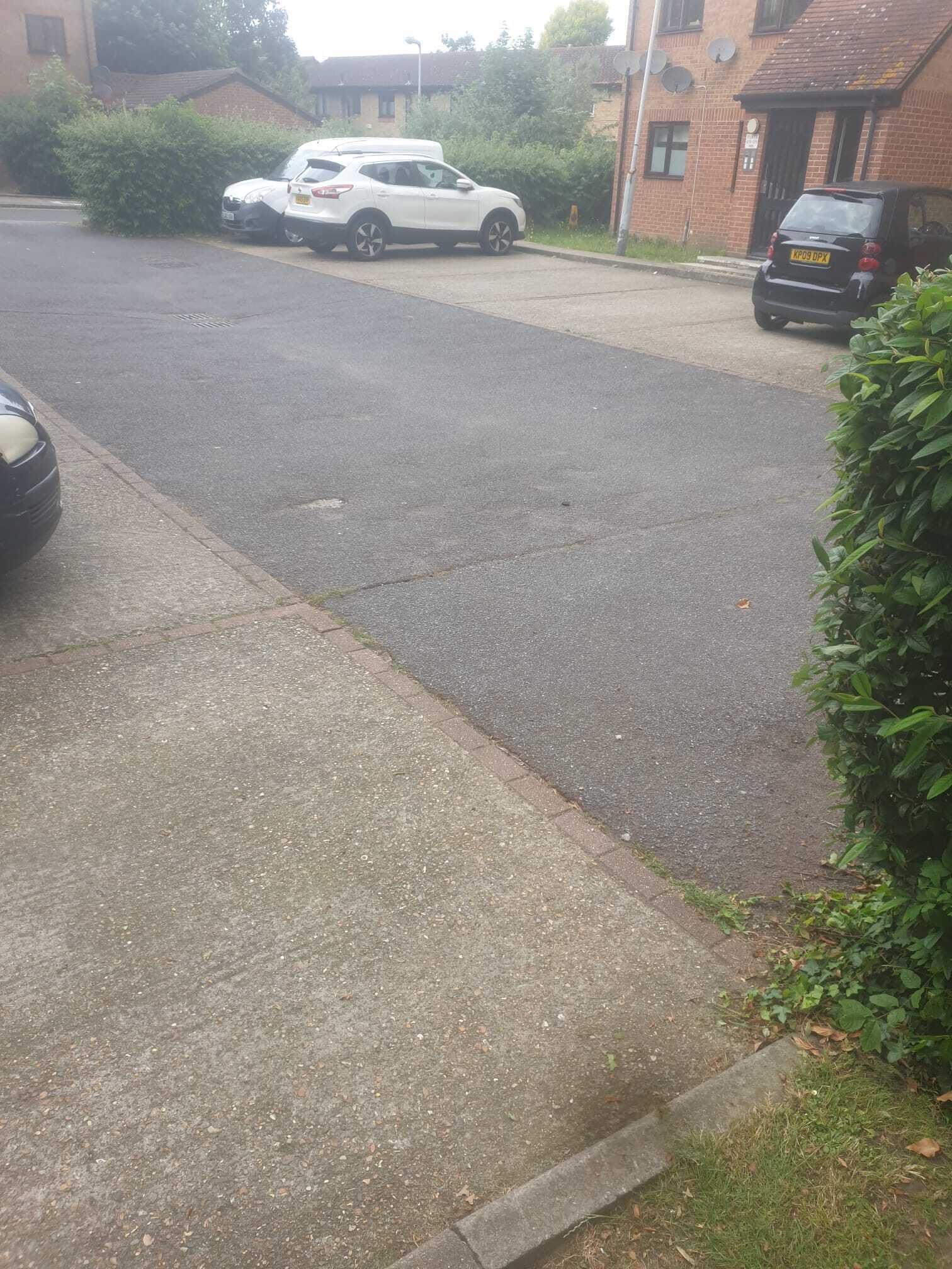 Una calle residencial con coches estacionados y casas.
