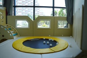 A child's play area with a trampoline, a bed, and windows with curtains. - Signature Beach at The Arena Cam Ranh (Cam Ranh)