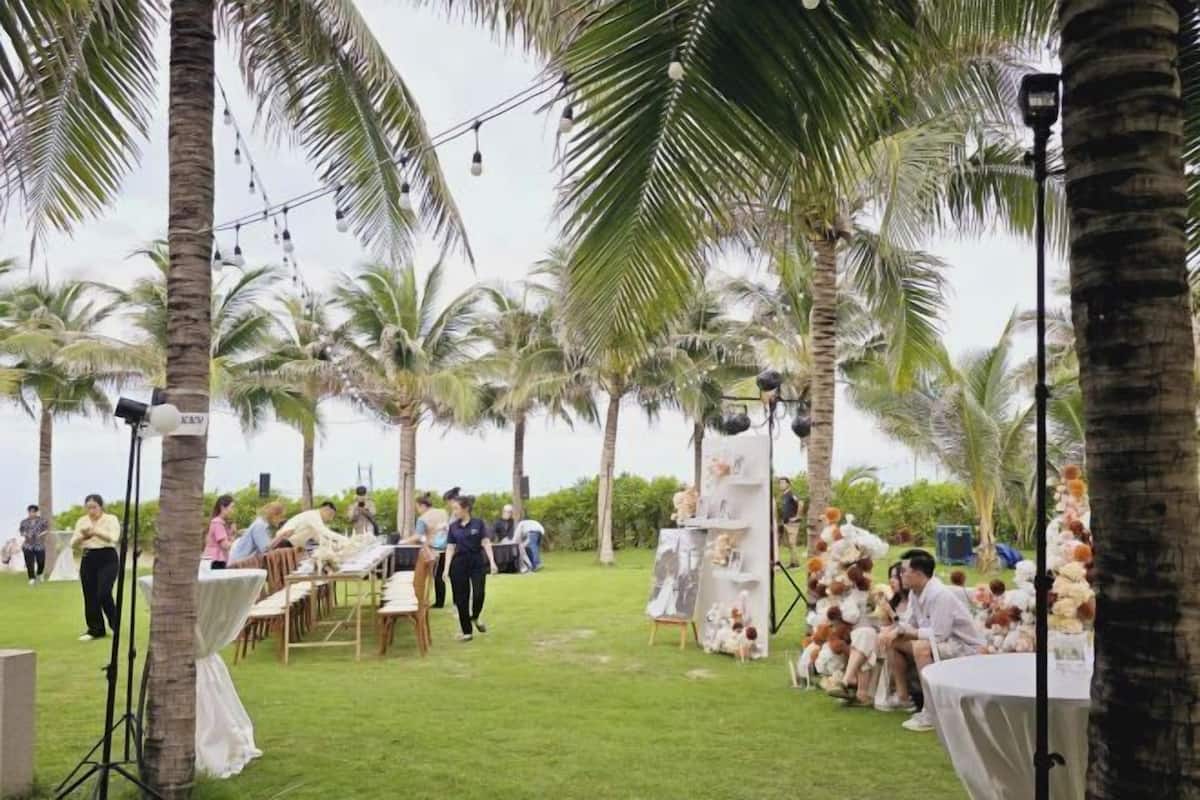 An outdoor event with palm trees, tables, and chairs set up for guests.