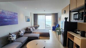 A modern living room with a sofa, a round coffee table, and a view of the sea through large windows. - Signature Beach at The Arena Cam Ranh (Cam Ranh)