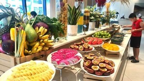 A buffet with various fruits and vegetables, including bananas, mangoes, and watermelon. - Signature Beach at The Arena Cam Ranh (Cam Ranh)