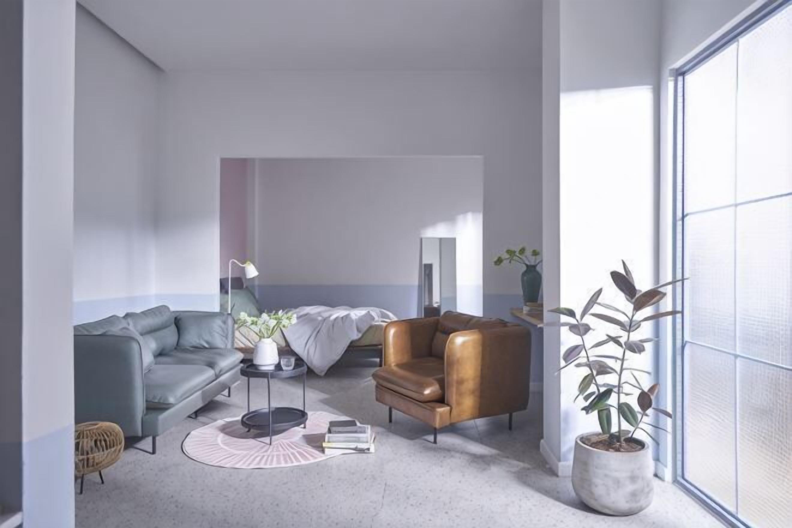A modern living room with a grey sofa, a brown armchair, a round coffee table, and a potted plant.