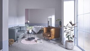 A modern living room with a grey sofa, a brown armchair, a round coffee table, and a potted plant. - Express by M Village Ly Chinh Thang, a brand of Modern Village Lifestyle (Ho Chi Minh City)