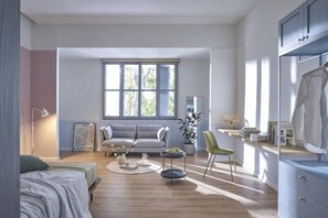 Ein modernes Wohnzimmer mit einer Couch, einem Esstisch, einem Stuhl und einem großen Fenster.