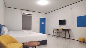 A hotel room with a bed, a desk, a chair, a TV, and an air conditioning unit. - RYB Hostel Phuket (Phuket)
