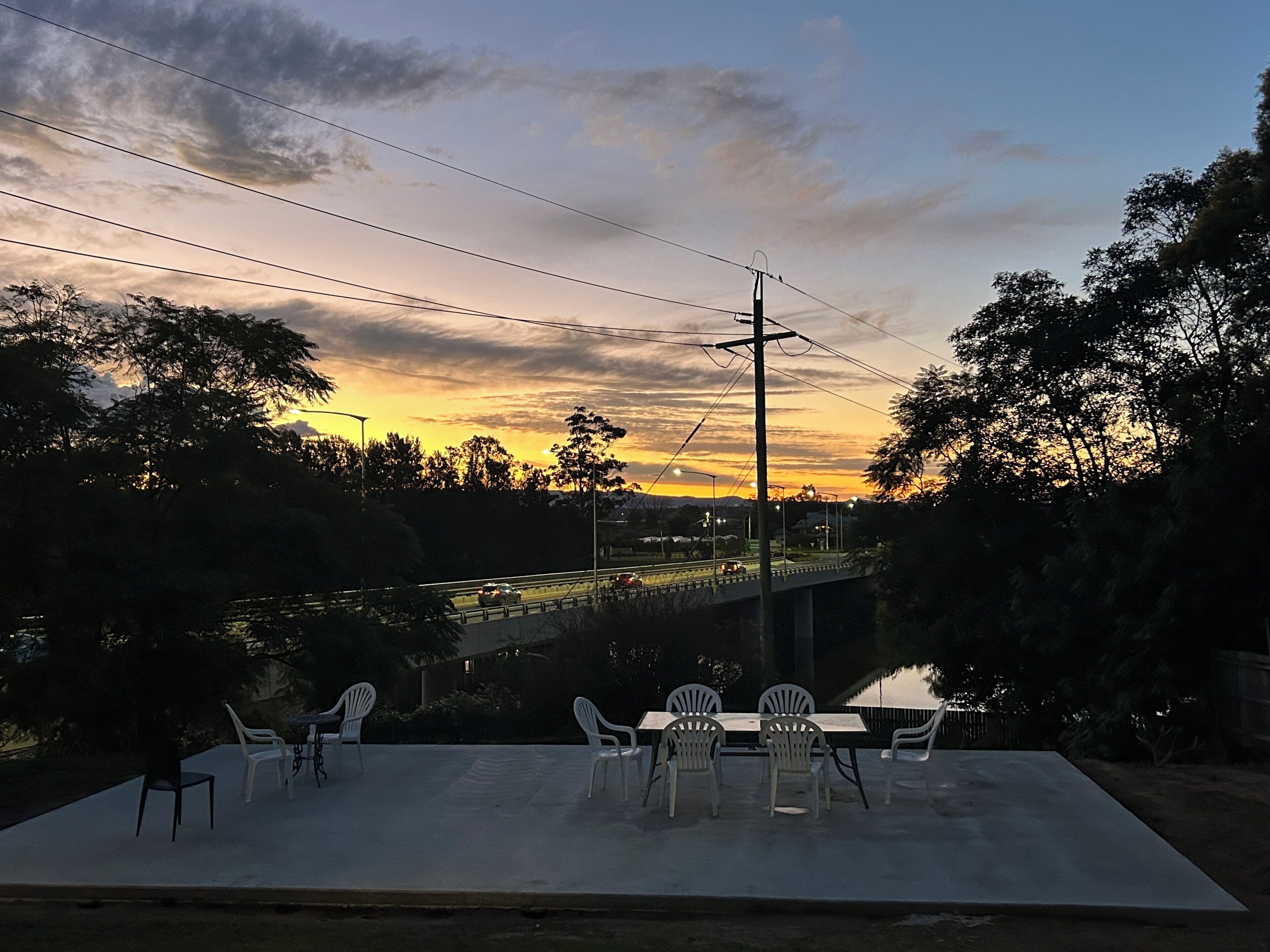 An outdoor patio with a table and chairs, overlooking a road and a bridge.