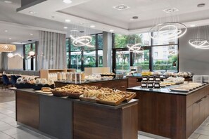 Un moderno comedor con una isla central, asientos y grandes ventanales.