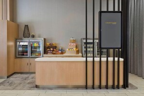 Una zona de recepción con mostrador, un cartel que dice 'COURTYARD' y un refrigerador lleno de bebidas.