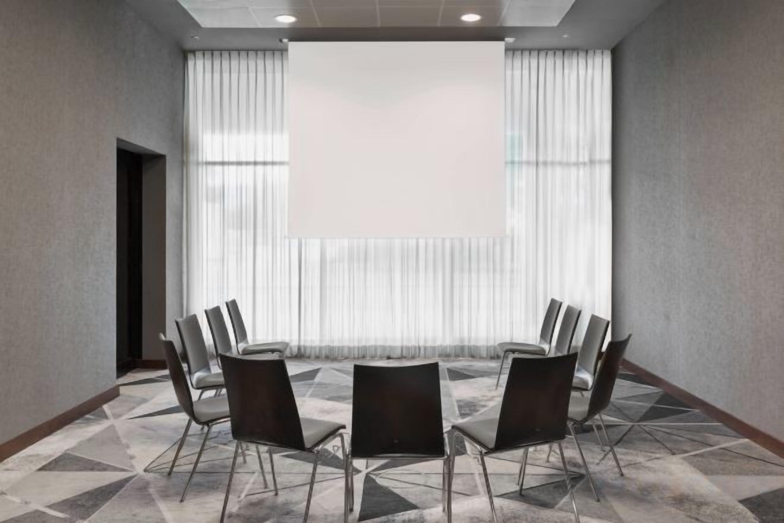 Una sala de conferencias con una pantalla grande, una mesa y sillas.