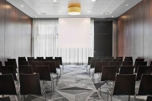 A conference room with rows of chairs, a patterned carpet, and a large window with curtains. - Courtyard by Marriott Munich City East (Munich)